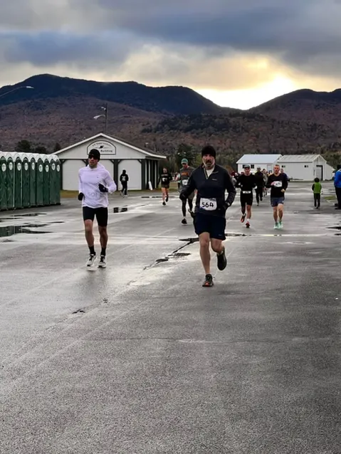 Runners on a road with mountains in the background during a race.