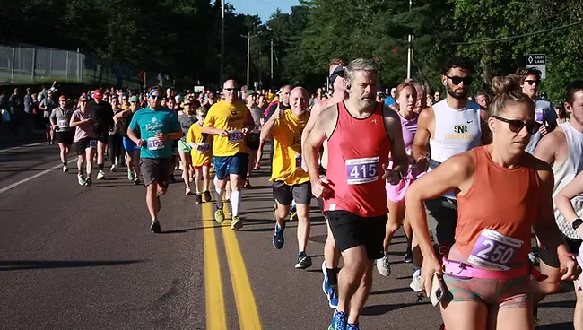 A group of runners on a road during a race, with some wearing bib numbers.