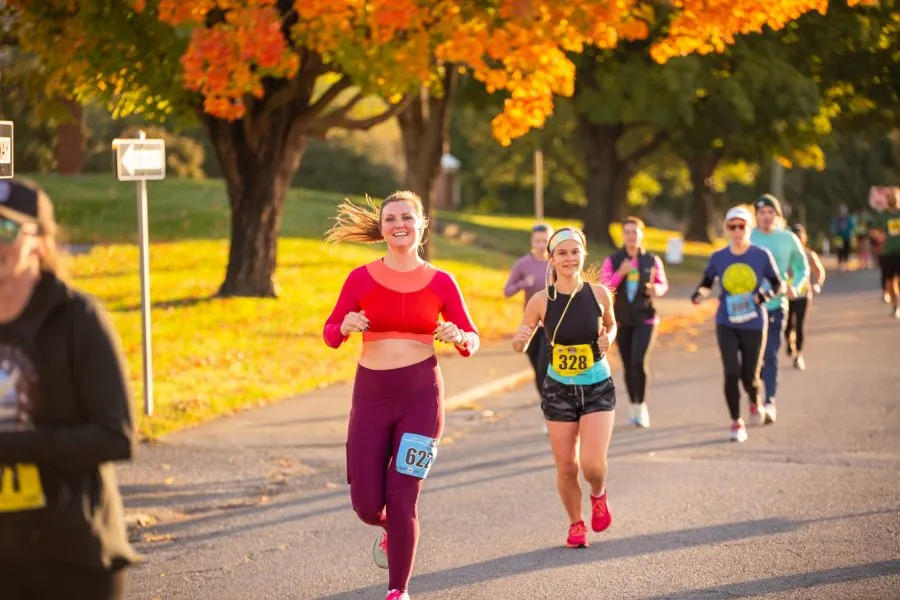 Runners participating in a race with colorful autumn trees in the background.