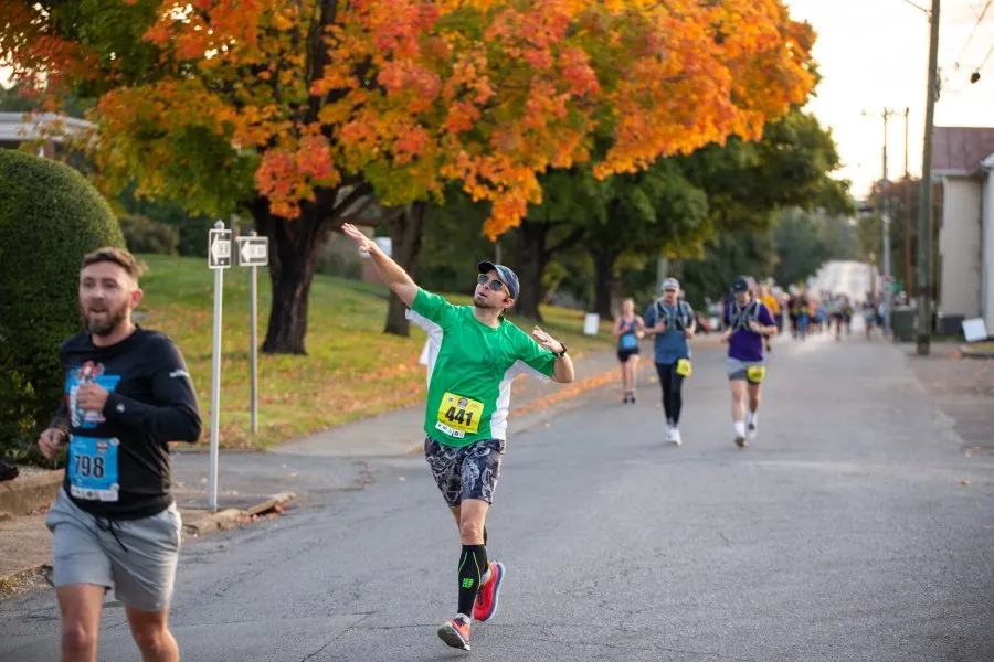 Runners participating in the LewisGale Salem Half Marathon on a road with colorful autumn trees.