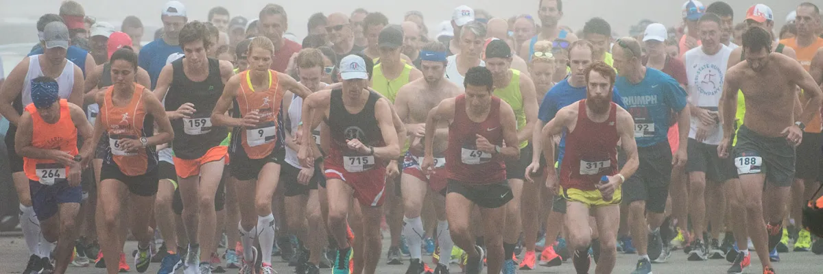 A large group of runners starting a race, with many participants visible in the foreground and background.