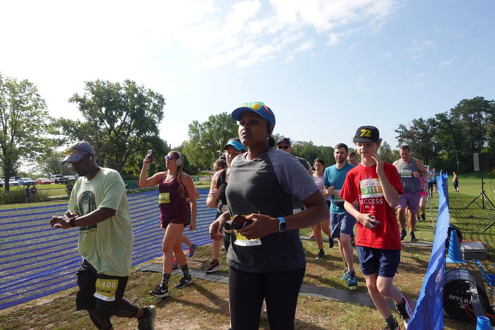 A group of runners are starting a race, with some looking ahead and others checking their watches.
