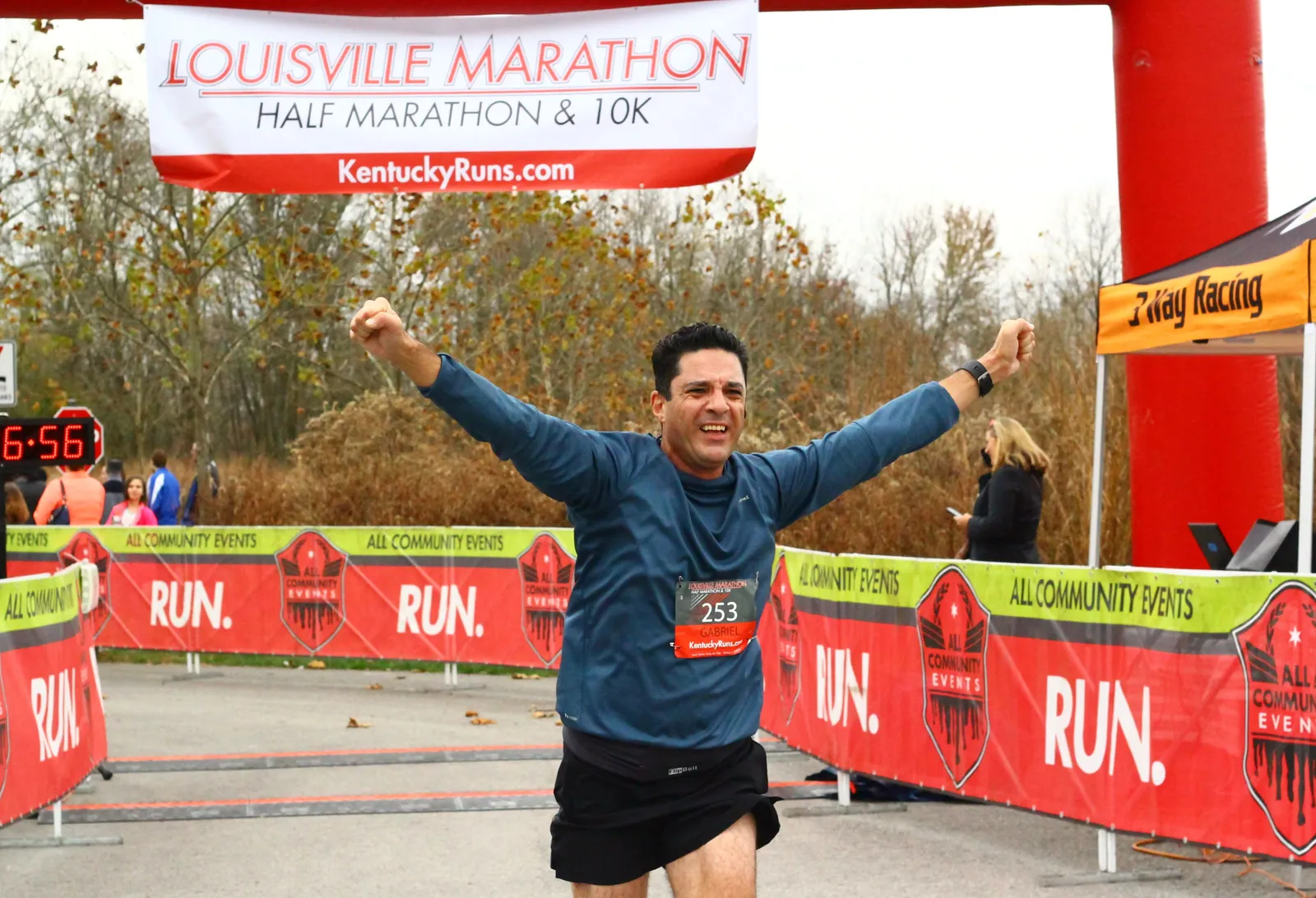 A runner with arms raised in celebration crosses the finish line at the Louisville Marathon, Half Marathon & 10K.