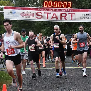 Runners starting a race, with a banner overhead that says 'START'.