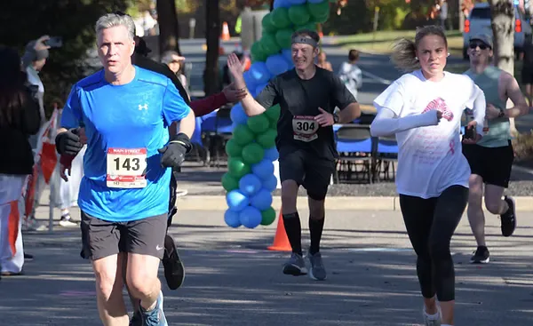 Runners crossing the start line under a balloon arch at the Main Street Half Marathon.