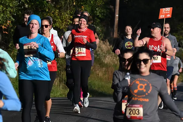 Runners participating in the Main Street Half Marathon, with some wearing bib numbers and others holding pace signs.