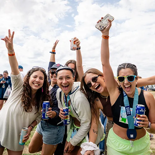A group of women smiling and cheering, holding drinks and wearing race medals.