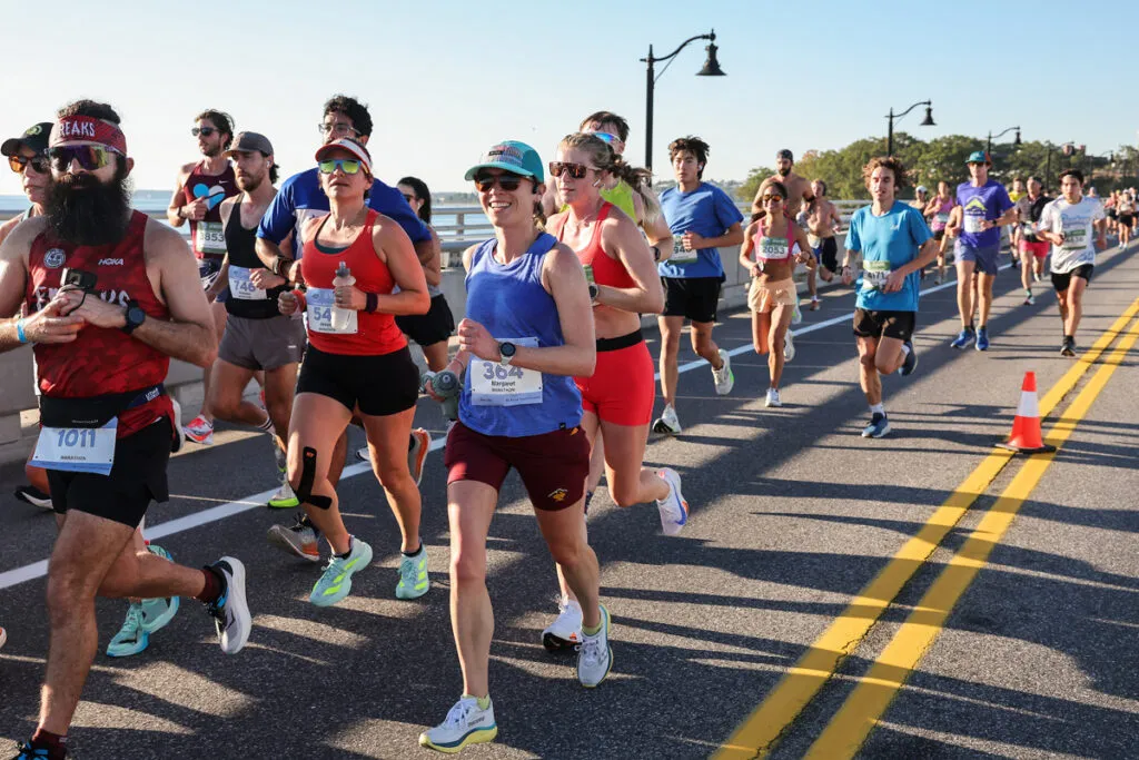 Runners on a bridge during a race, with clear blue skies and sunshine.