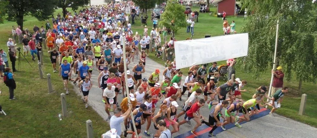 A large group of runners are starting a race, with many participants visible at the start line and stretching back into the distance.