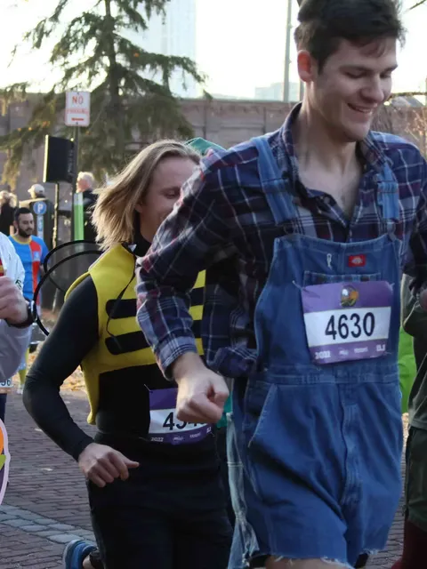 Runners in costumes, one dressed as a bee and another in overalls, participating in a race.