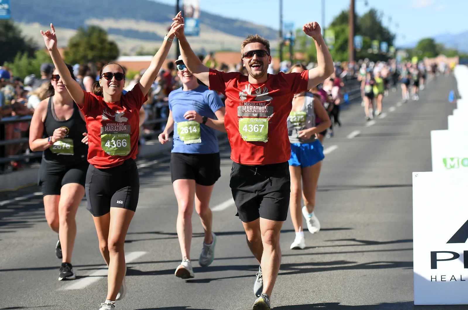 Runners celebrating with arms raised at the finish line of the Missoula Half Marathon.