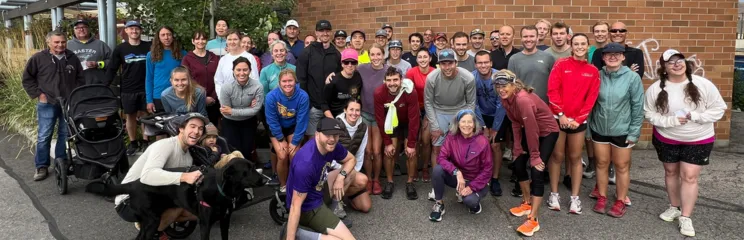 A large group of people, many wearing athletic clothing, posing for a photo outdoors.
