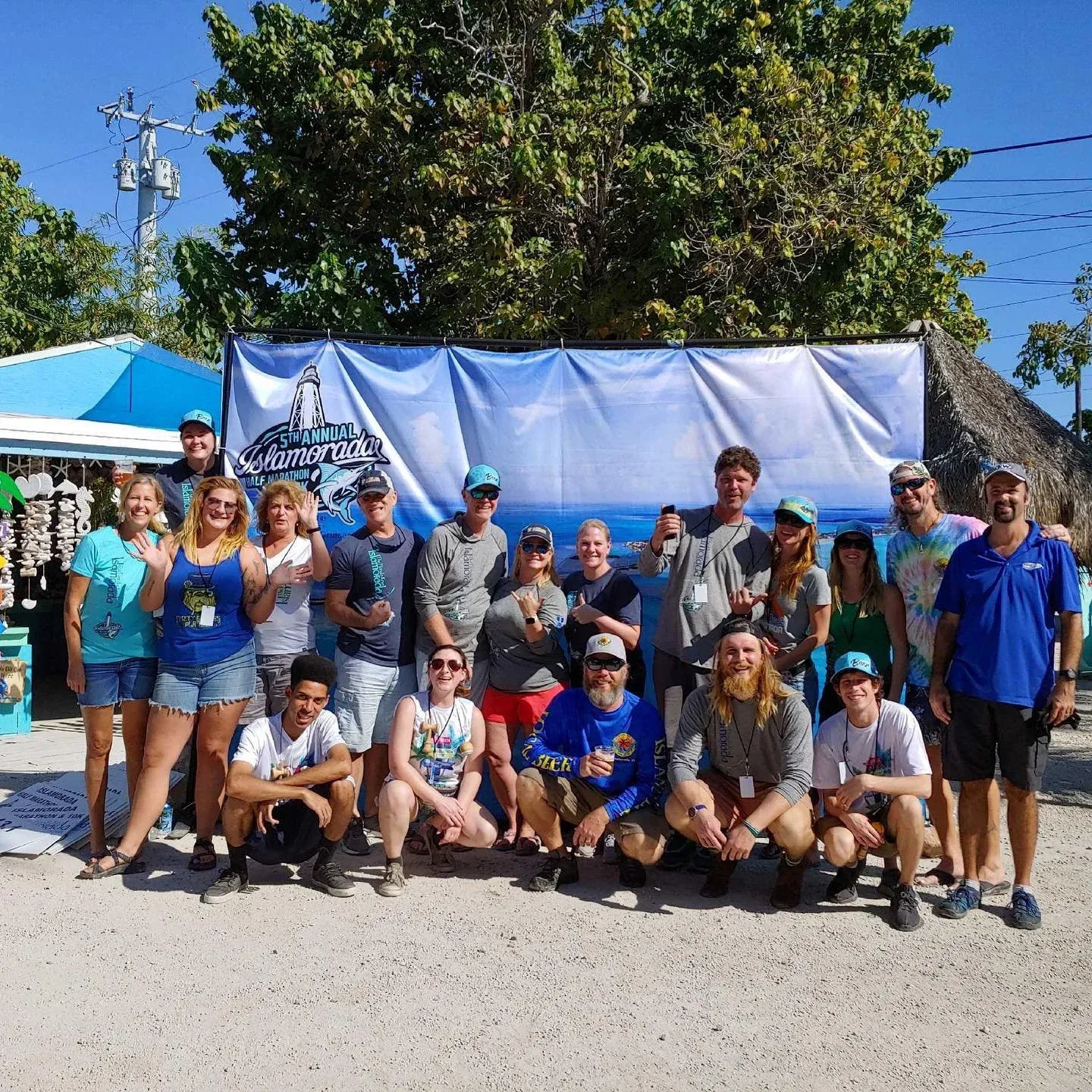 A group of runners posing for a photo in front of a race banner that says '5th Annual Islamorada Half Marathon'.