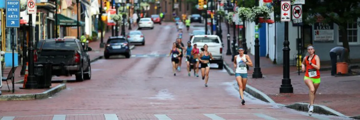 Runners competing in a race on a brick-paved urban street.