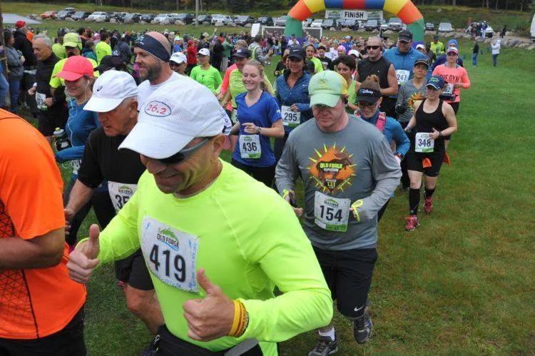 Runners in bright shirts and hats start a race under a colorful archway with 'FINISH' visible.