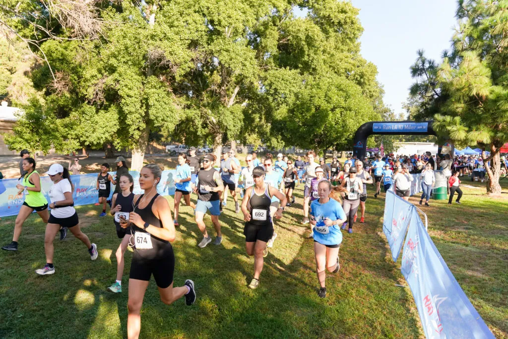 Runners starting a race, with an inflatable archway in the background and trees lining the course.