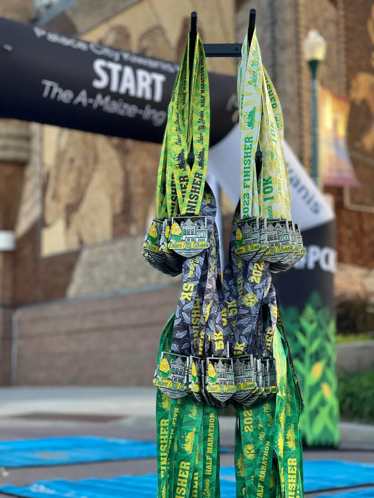 Race medals hanging in front of a 'START The A-Maize-Ing' banner.