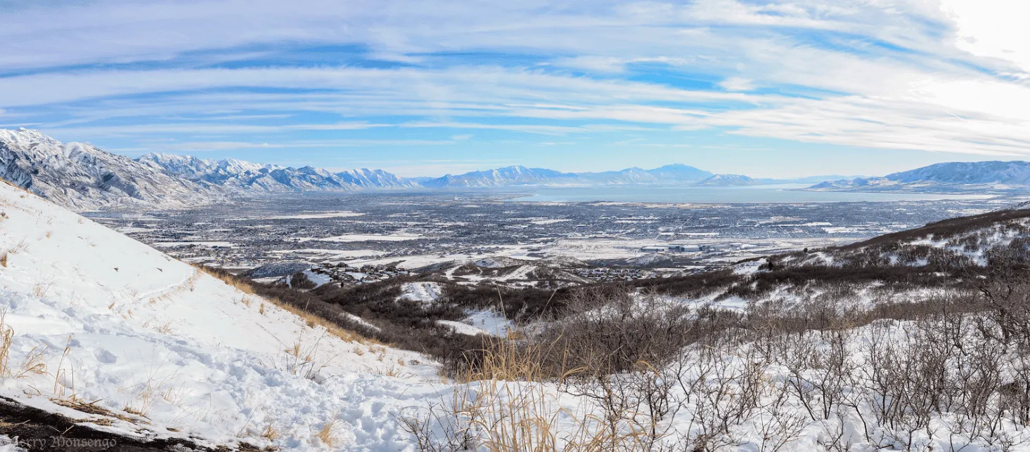 Panoramic view of a snow-covered valley with mountains in the background and a city nestled below.