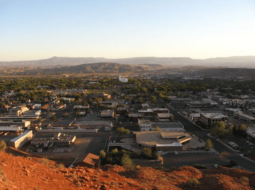Panoramic view of St. George, Utah, with buildings and distant mountains under a clear sky.