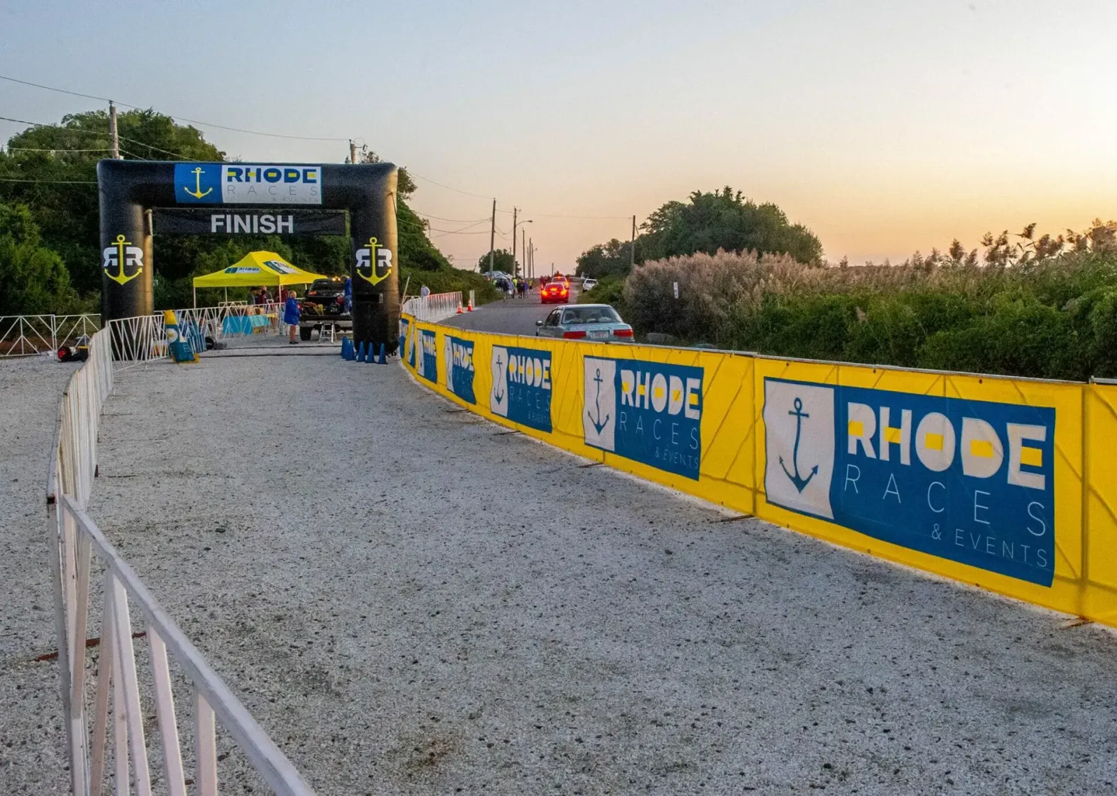 Finish line archway with 'Rhode Races' branding and yellow banners along the course.