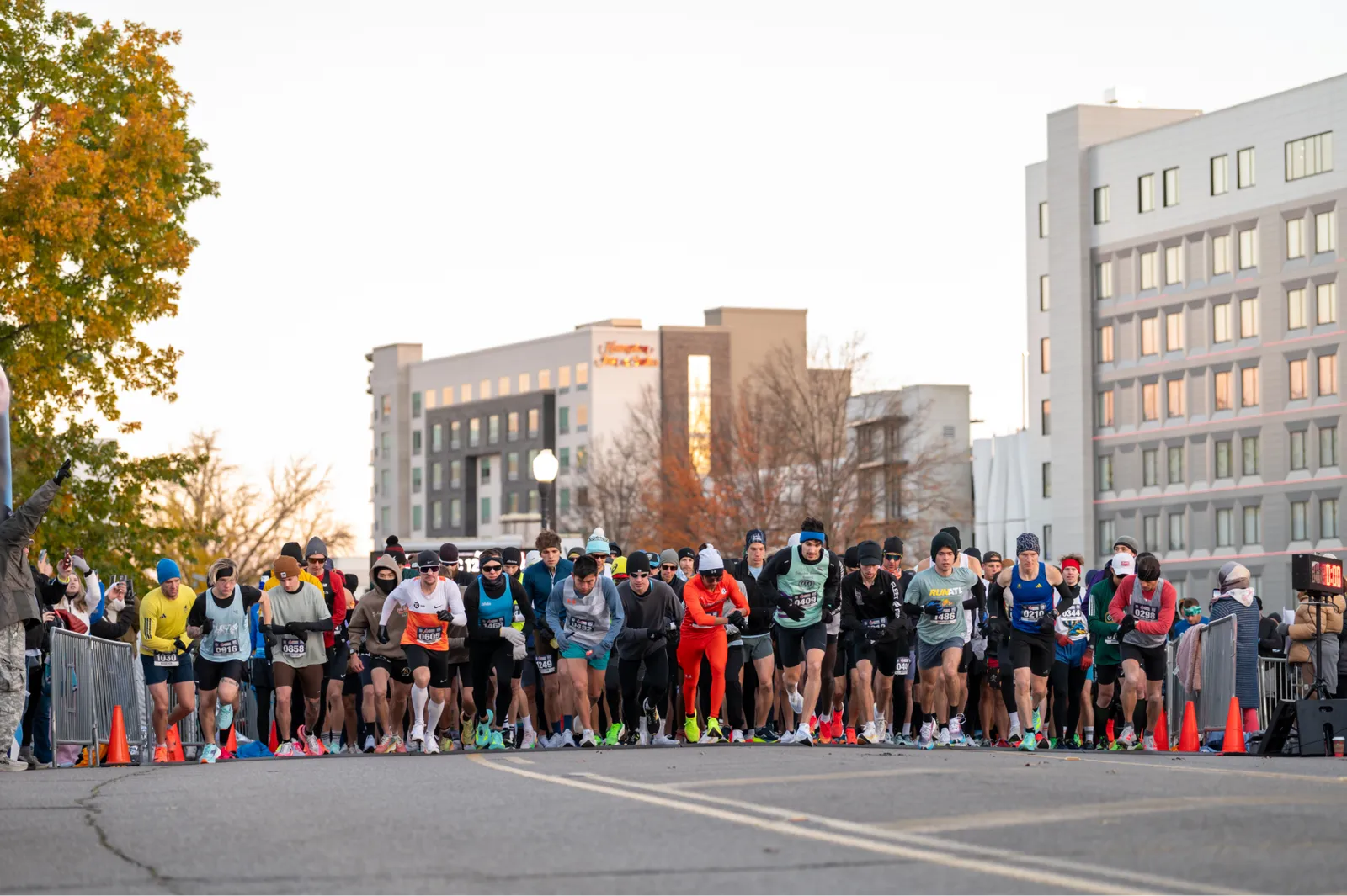 Runners at the starting line of a race, with buildings in the background.