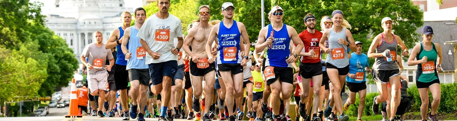 A group of runners in a race, with a large building in the background.