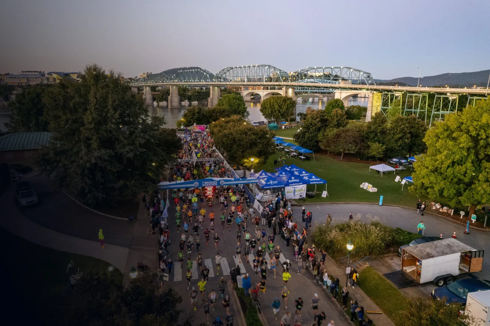 Runners at the start line of the 7 Bridges Marathon with a large bridge in the background.