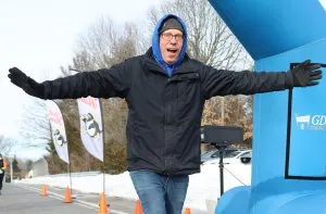 A man with his arms outstretched in excitement at the start line of a race.