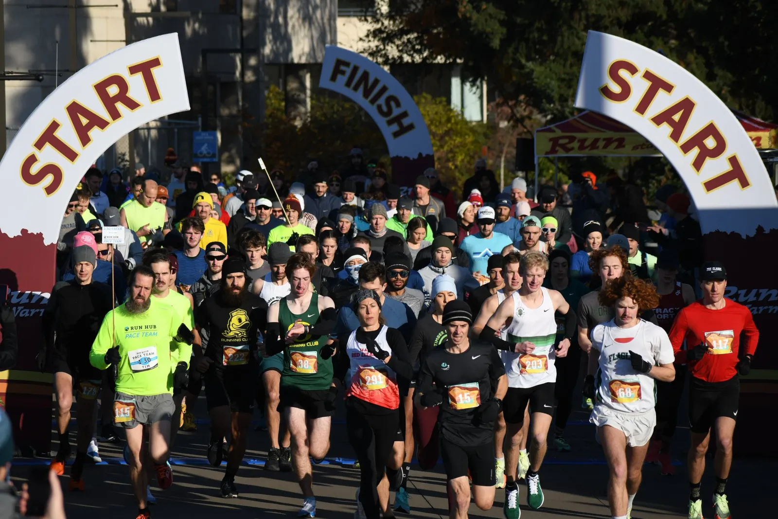 A large group of runners are starting a race, with 'START' arches visible above them.