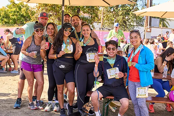A group of smiling runners, some wearing medals, pose for a photo after completing the Santa Barbara Half Marathon.