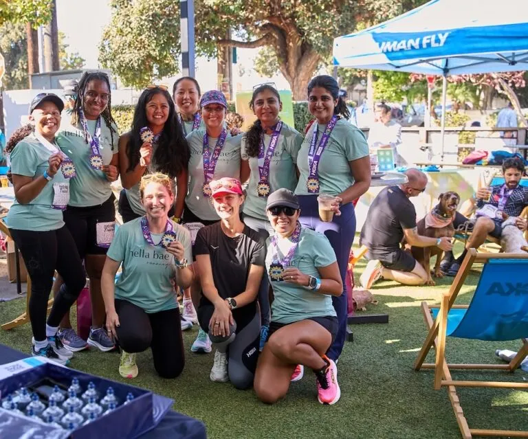 A group of women, some wearing medals, smiling and posing for a photo after a race.