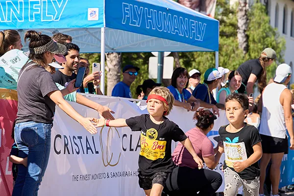 Children running and receiving high-fives from spectators at the Santa Barbara Half Marathon.