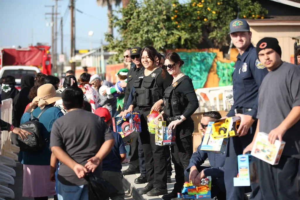 Law enforcement officers and community members holding toys during a giveaway event.