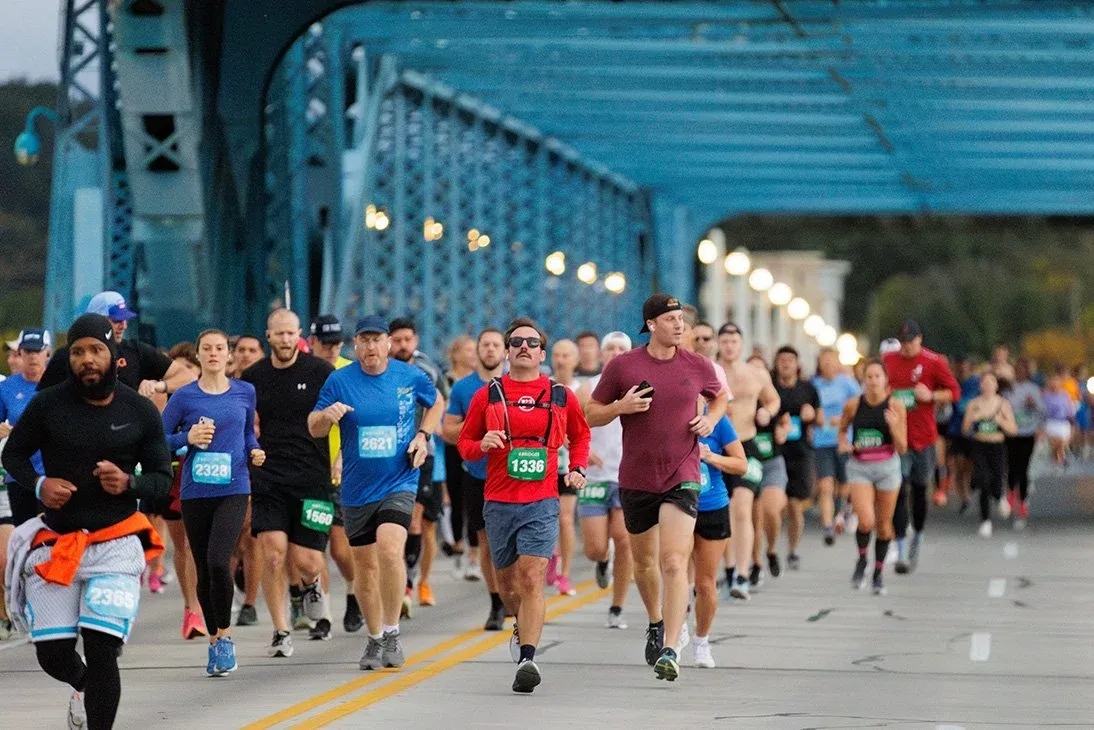 A group of runners race across a blue bridge during the Seven Bridges Marathon.