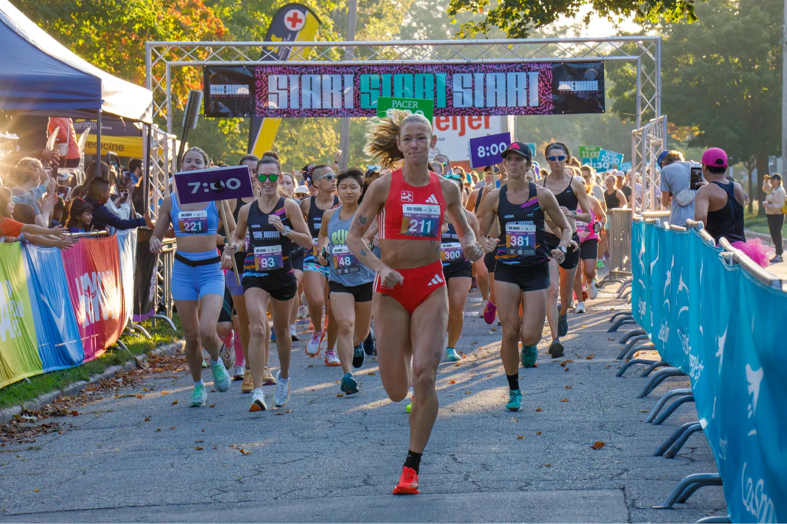 Runners starting a race, with a banner overhead that says 'START START START'.