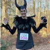 Runner dressed as Maleficent with bib number 206, smiling and holding a small object.