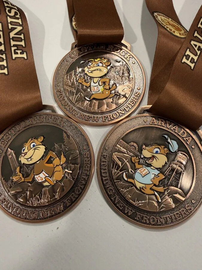 Three race medals with prairie dog mascots on ribbons.