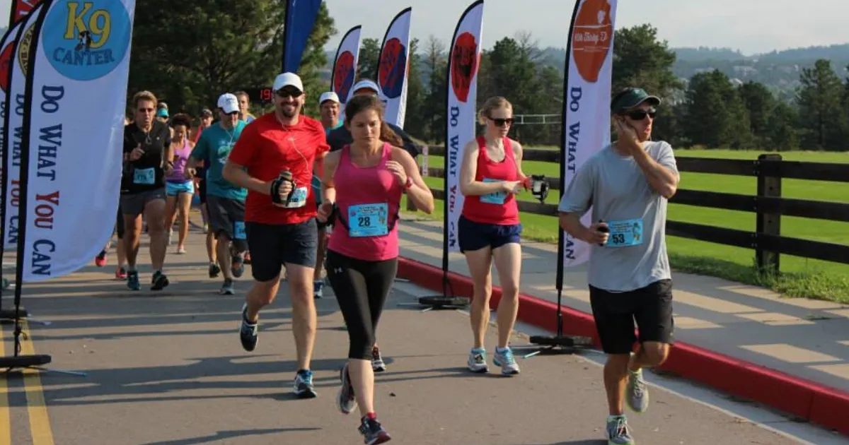 Runners participating in a race, with several runners in the foreground and more in the background, along with race banners.