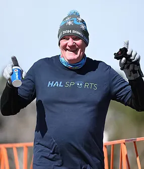 A smiling runner wearing a blue beanie and t-shirt, holding a cup of Pepsi and giving a thumbs up.