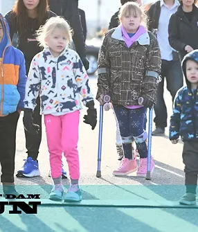 Children walking at the start of a race, one on crutches.