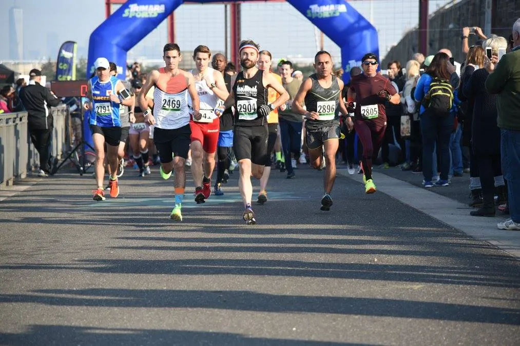 Runners crossing the start line under a blue archway at the Bay Ridge Half Marathon.