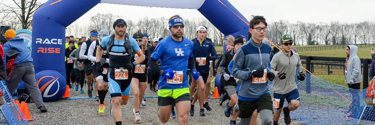 Runners starting a race under a blue archway with 'RACE RISE' text.
