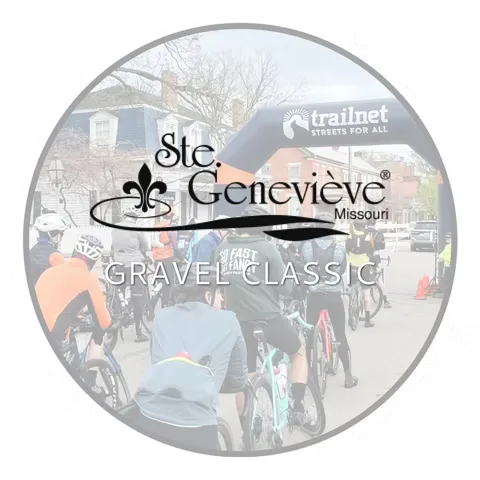 Cyclists gathered at the start line of the Ste. Genevieve Gravel Classic, with an inflatable archway in the background.