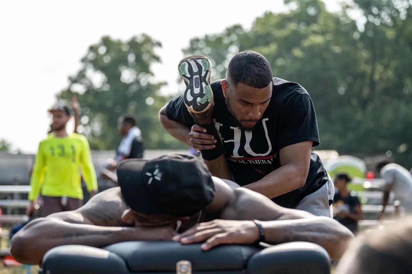 A runner receiving a leg stretch from a physical therapist after a race.