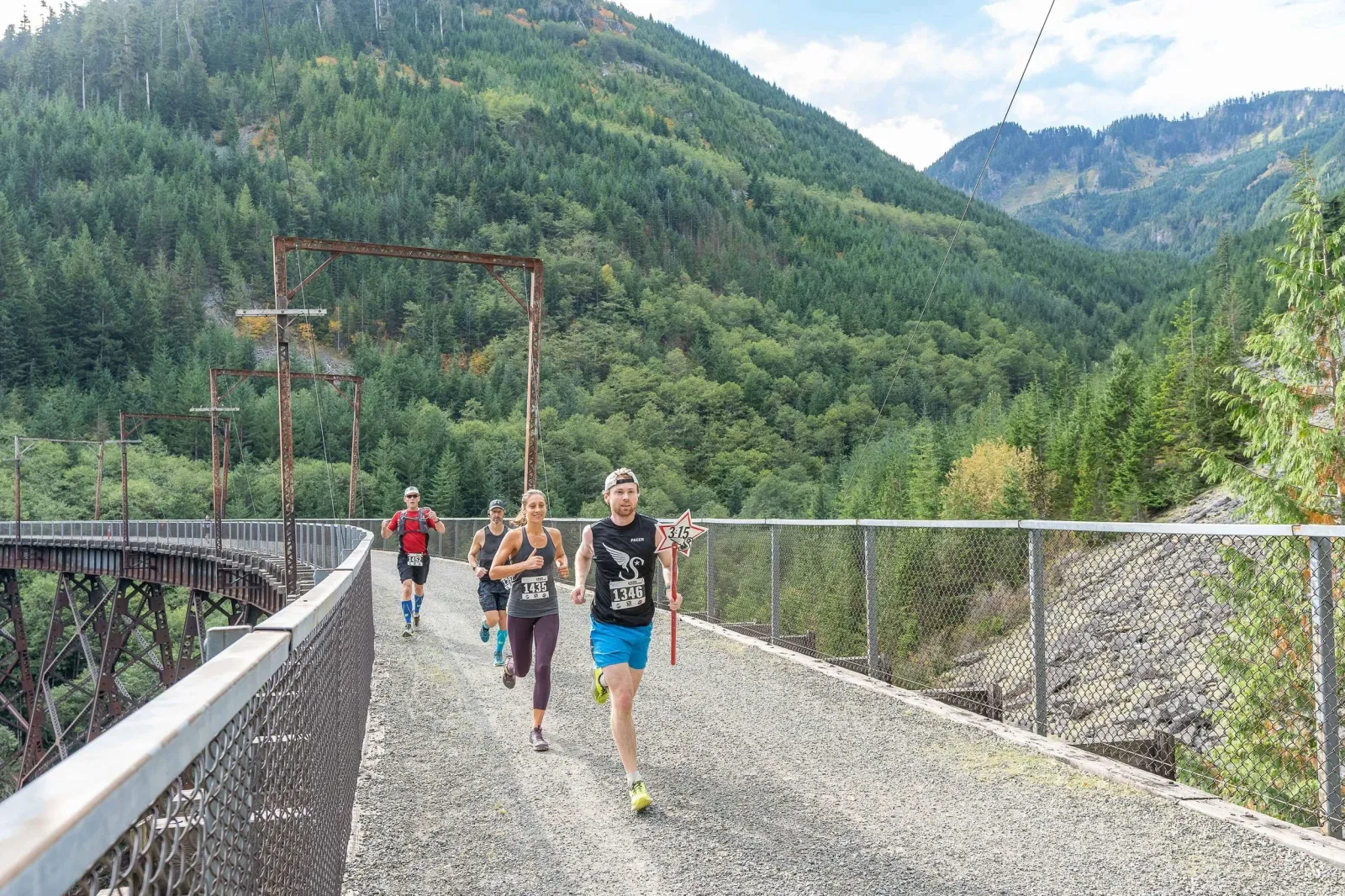 Runners on a bridge with a scenic mountain backdrop during the Twilight at the Bay race.