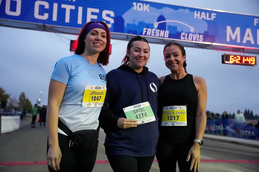 Three women smiling at the finish line of the Two Cities Marathon.