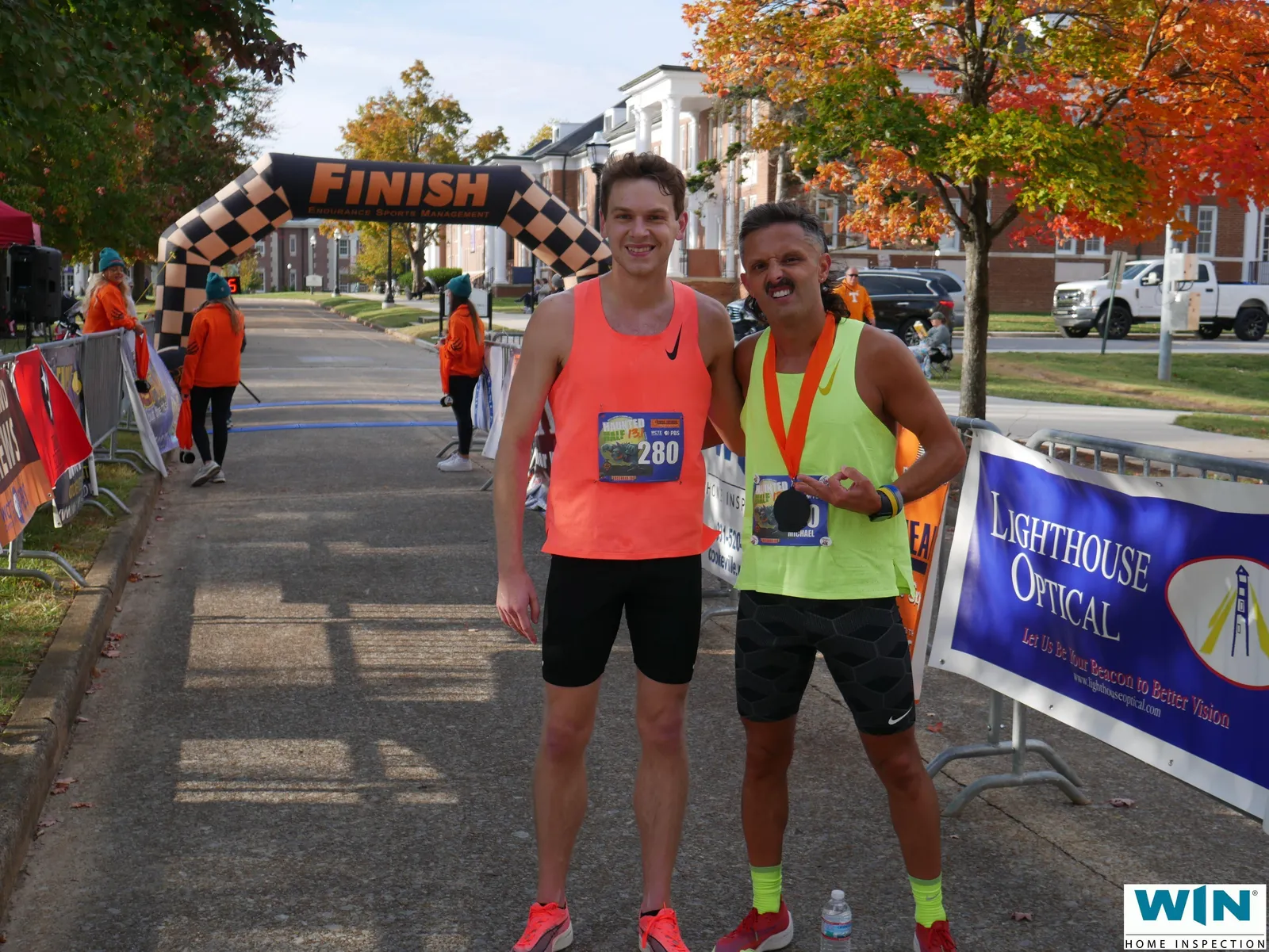 Two male runners smiling at the finish line of the Upper Cumberland Haunted Half Marathon, one wearing a medal.