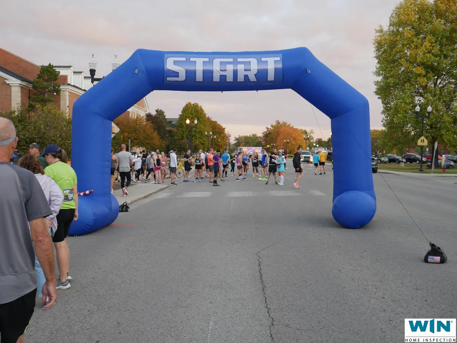 Runners gathered at the start line of a race, with a blue inflatable archway overhead.