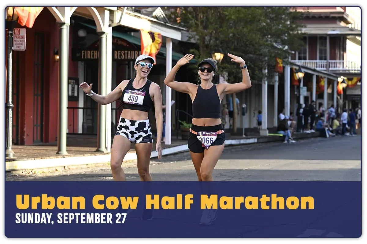 Two female runners smiling and waving at the camera during the Urban Cow Half Marathon.