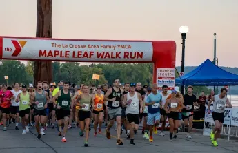 Runners starting the YMCA Maple Leaf Walk Run under an inflatable archway.